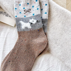 Detail of wool blend socks with colorful nep yarn pattern and plush puppy bow decoration