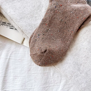 Detail of coffee brown flecked knit socks with cozy texture on minimalist background