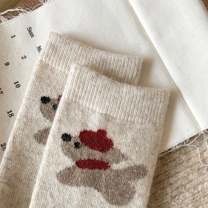 Close-up of beige wool socks with cute cartoon puppy embroidery and thick knit texture