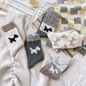 Flat lay of thermal wool socks with dog embroidery and bows on a warm winter backdrop