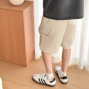 Detail view of khaki cargo shorts showing durable cotton fabric and large side pocket