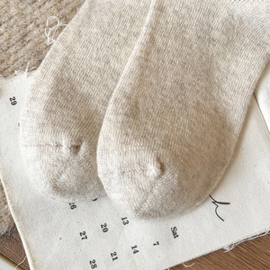 Close-up of seamless toe stitching on cream wool blend socks with warm knit texture