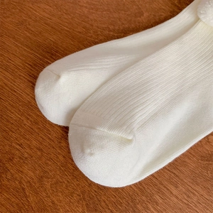 Close-up of white ribbed knit socks with vertical texture on a wooden background
