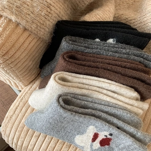 Close-up of thick wool crew socks in neutral tones with cute puppy embroidery detail