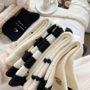 Détail de chaussettes épaisses à pois avec broderie de chiot sur fond en laine