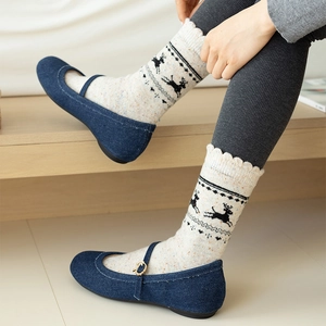 Close-up of white wool socks with black reindeer patterns and wavy cuffs in blue shoes