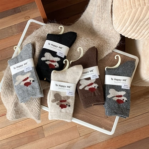 Detail of five pairs of wool socks featuring cute cartoon bird patterns in earthy tones