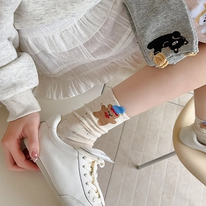 Detail of cream bear embroidered crew socks with colorful dots worn with white sneakers