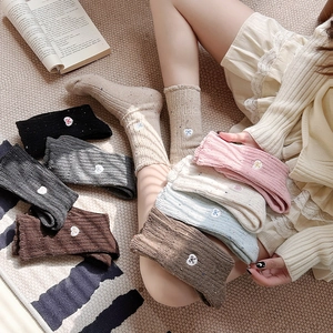 Close-up of thick knit wool socks featuring delicate bow embroidery and vintage texture