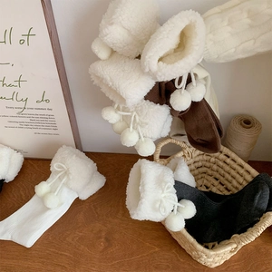 Close-up of ribbed knit socks with plush fur cuffs and decorative pom-pom drawstrings