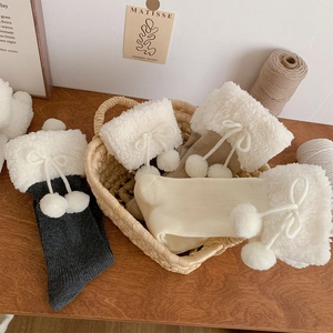 Close-up of cozy knitted winter socks with white faux fur trim and cute pom-pom ribbons