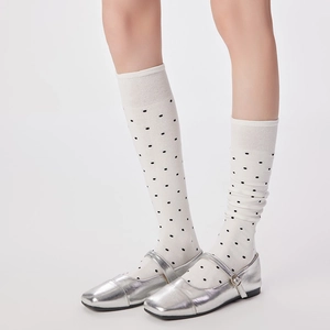 Détail de chaussettes blanches à pois portées avec des chaussures Mary Jane argentées