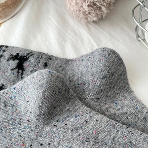 Detail of grey wool blend socks with knitted reindeer patterns and colorful tweed flecks