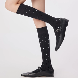 Détail de chaussettes mi-mollet noires à pois blancs portées avec des chaussures Mary Jane