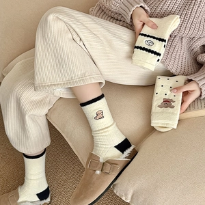 Détail des chaussettes thermiques crème avec broderie de chiot et motifs à pois noirs