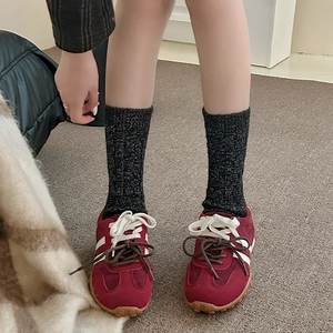 Détail de chaussettes en laine avec baskets en daim bordeaux, bandes blanches et paillettes