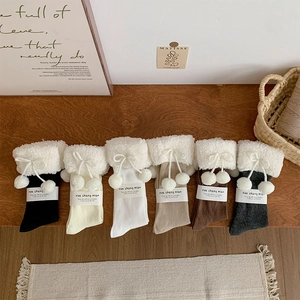 Close-up of six pairs of Lolita style thick socks with fluffy pompoms and bows