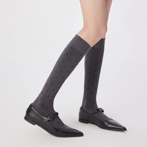 Gros plan de chaussettes hautes gris foncé à pois noirs avec chaussures Mary Jane