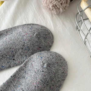 Close-up of thick grey wool socks with colorful nep yarn texture for winter warmth