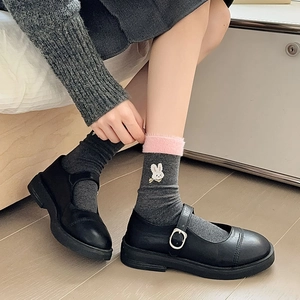 Détail de chaussettes en tricot gris avec broderie lapin et bordure en fausse fourrure