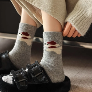 Detail of gray wool socks featuring a cute puppy pattern with a red beret for winter