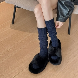 Detail of dark blue ribbed thermal socks paired with black fuzzy faux fur slippers