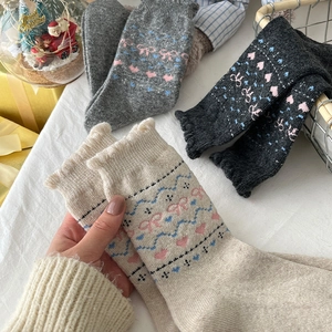 Close-up of wool socks featuring cute pink bows, heart patterns and ruffled edges