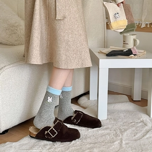 Détail de broderie lapin sur chaussettes en coton colorées et chaussures d'hiver