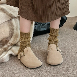 Gros plan détaillé des sabots en daim beige portés avec des chaussettes en tricot