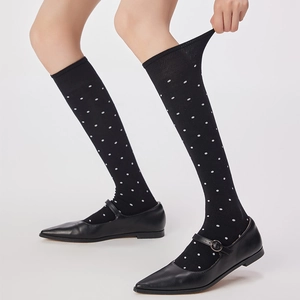 Gros plan sur des chaussettes hautes noires à pois blancs avec revers et chaussures Mary Jane