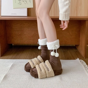 Detail of coffee brown ribbed socks with white faux fur cuffs and fuzzy pom-poms