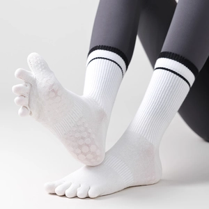 Dettaglio dei gommini antiscivolo in silicone su calze da yoga bianche a cinque dita