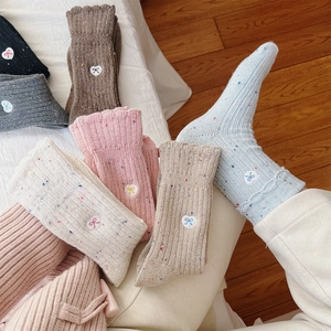 Detailed close-up of wool knit socks with heart embroidery and colorful flecks in six colors