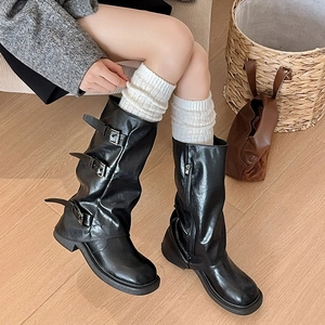 Detail of black leather boots with metal buckles and warm white knitted crew socks