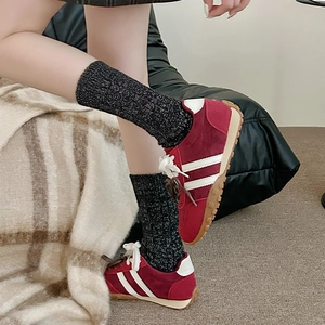 Gros plan de baskets en daim rouge avec bandes blanches et chaussettes grises brillantes