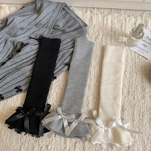 Detail of knit leg warmers with ribbon bows and flared hems in balletcore style