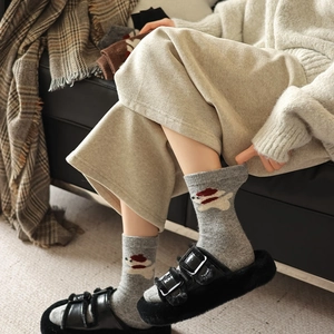 Detailed close-up of wool socks with a cute white bear embroidery on dark grey knit