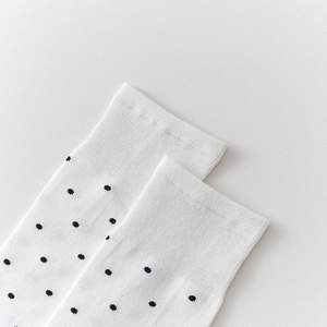 Détail de chaussettes blanches tricotées à pois noirs avec une bordure en côte élastique