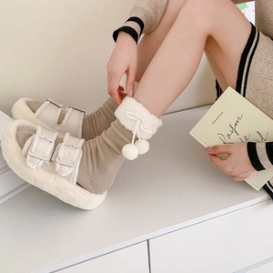 Close-up of lolita style socks with white fur trim and plush pom-poms for winter