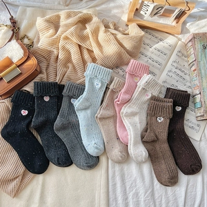 Detailed view of colorful wool knit socks with heart bow embroidery and ribbed cuffs