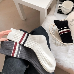 Detail of three pairs of ribbed knit crew socks in white, gray, and black with stripe accents