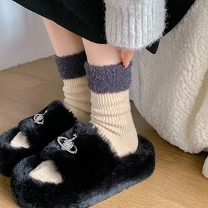 Gros plan sur des chaussons noirs en peluche avec boucle brillante et chaussettes en maille
