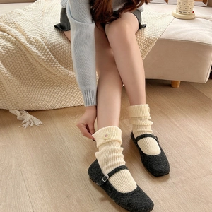 Close-up of cream knit thick socks with button detail paired with grey Mary Jane shoes
