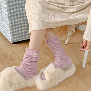 Close-up of lavender knit mid-calf socks with flower patch and cozy plush slippers