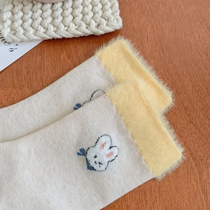 Détail de chaussettes lapin brodées avec revers en fausse fourrure jaune et texture