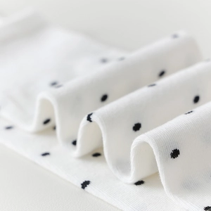 Gros plan sur le tissu tricoté blanc à pois noirs montrant la texture douce détaillée
