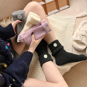 Close-up of thick knitted crew socks with cute decorative buttons and ribbed texture