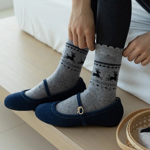 Detail of wool socks with reindeer pattern paired with blue Mary Jane bow shoes