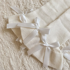 Detailed texture of rib-knitted leg warmers with delicate white satin bow accents