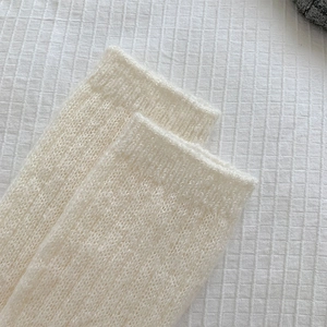 Close-up of fluffy cream knit calf socks featuring a ribbed cuff and soft wool texture